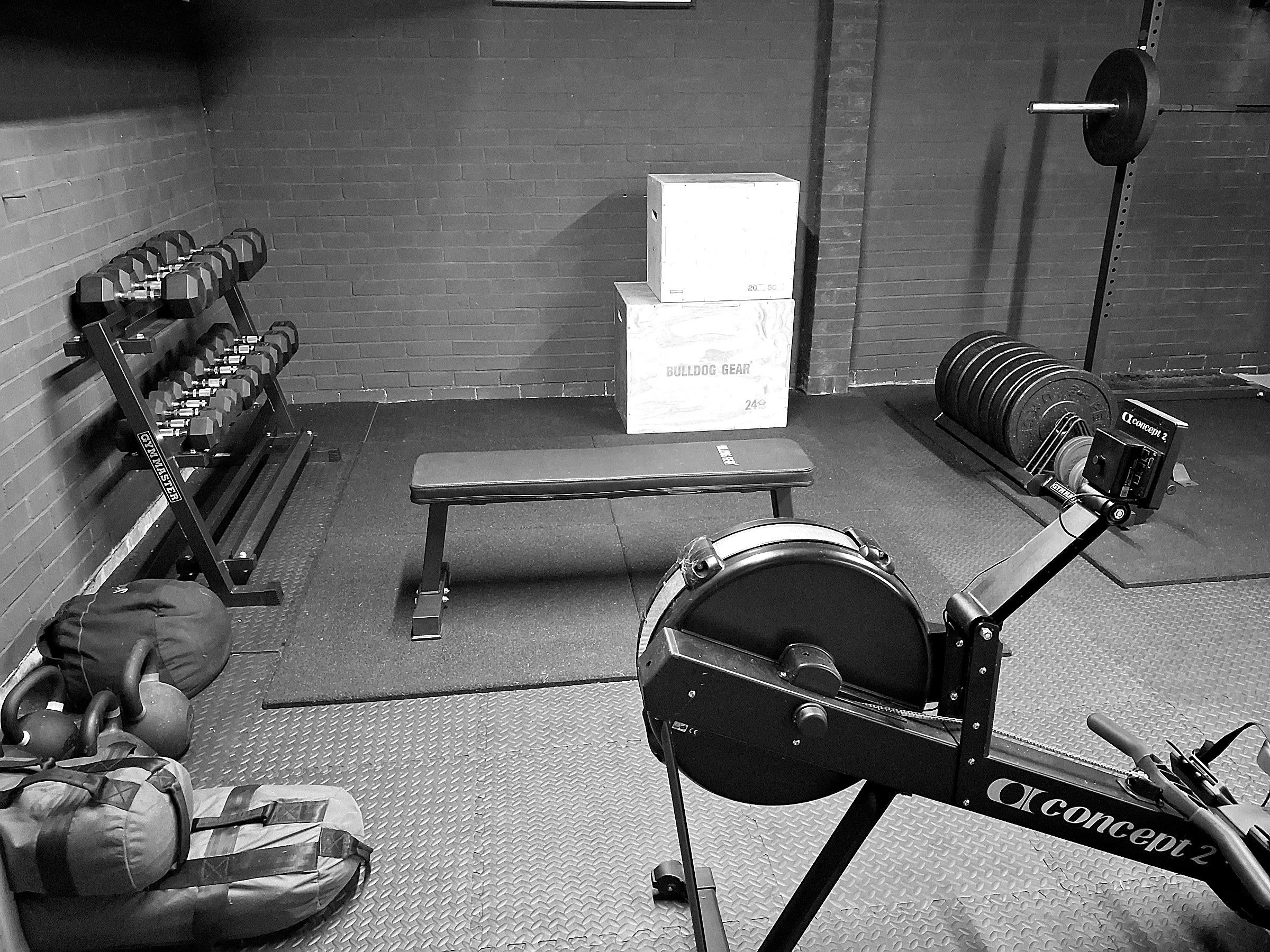 Kettlebells and sandbags beside the dumbbell rack in the garage studio
