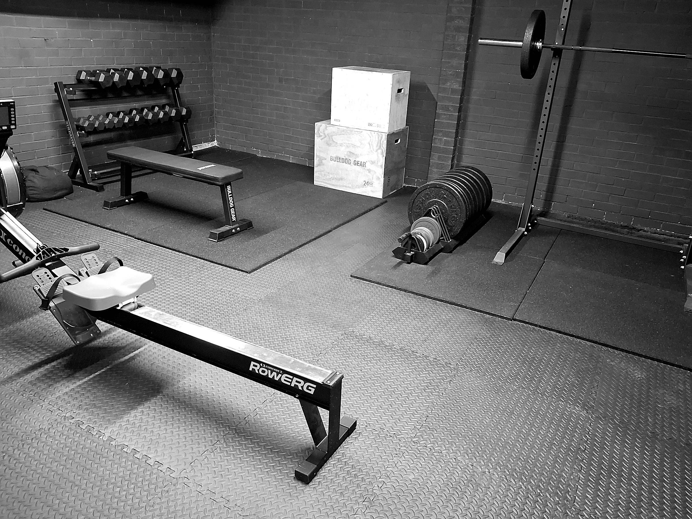 The garage studio in Whickham, with a rower, bench, dumbbells and a squat rack