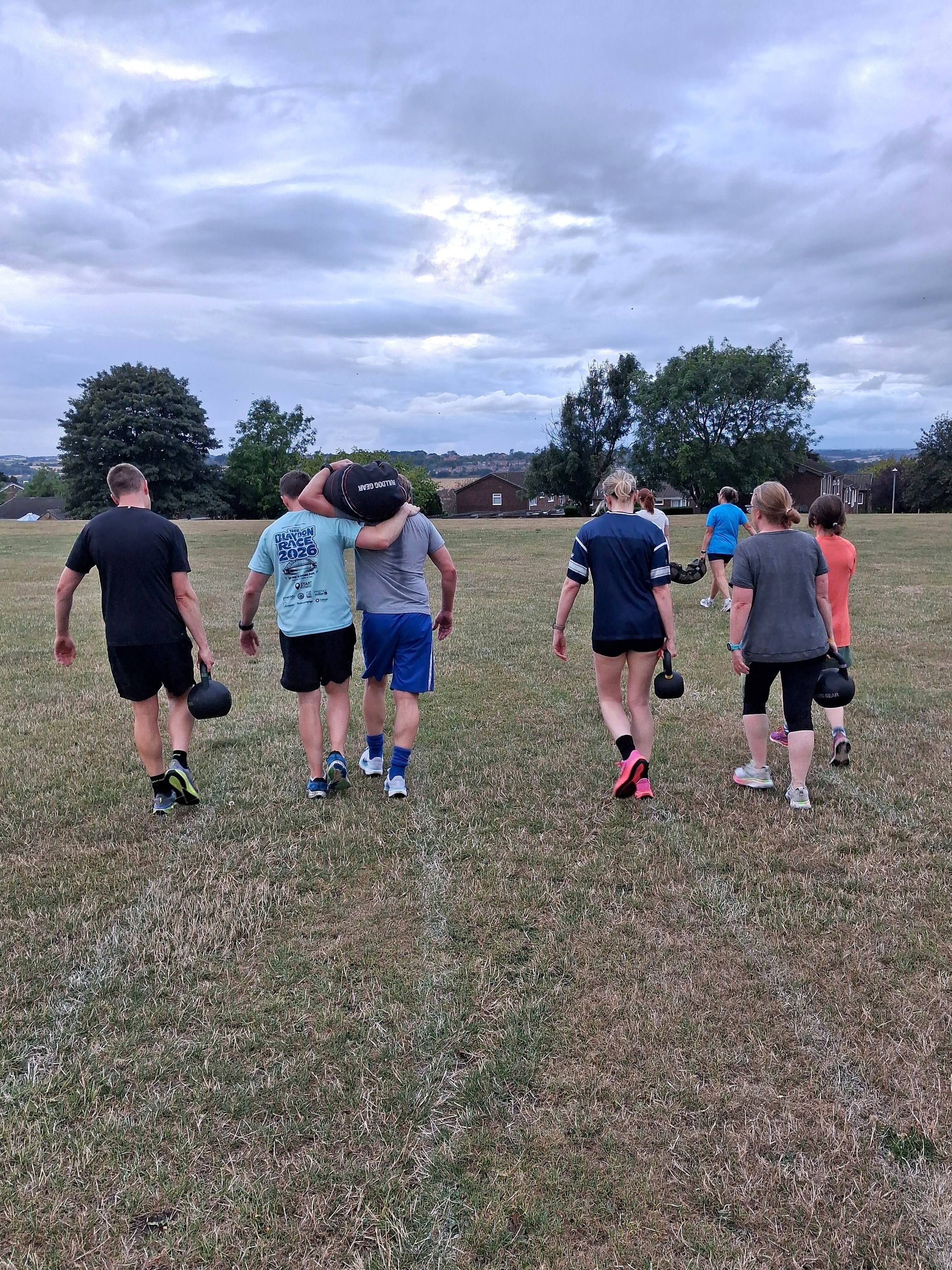 A CommFit group walking away across the valley at dusk after a class